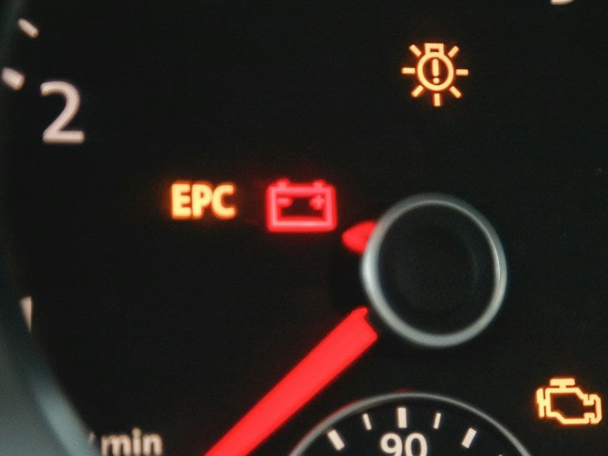 Close-up of a lit battery warning symbol on a dashboard. Stock photo.